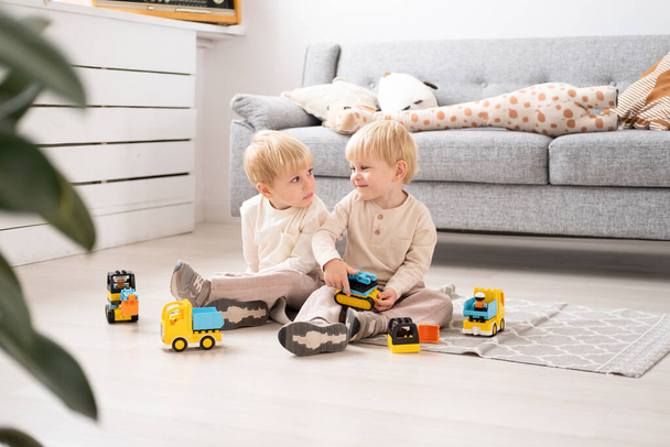 二つの面白い男の子兄弟双子遊びとともにおもちゃの車コンストラクターでリビングルーム - 写真・画像