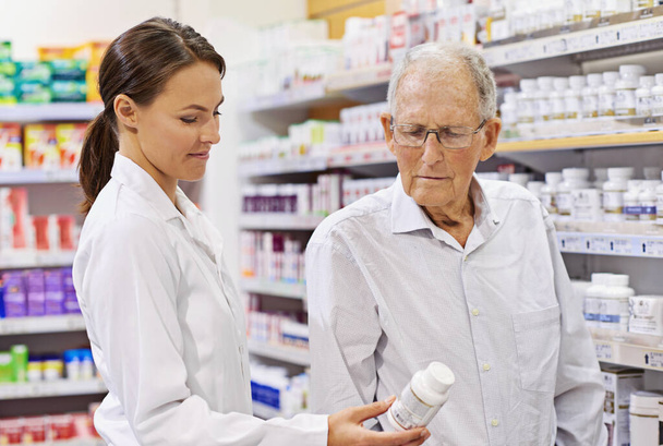 Sharing her wealth of knowledge. Shot of a young pharmacist helping an elderly customer. - 写真・画像