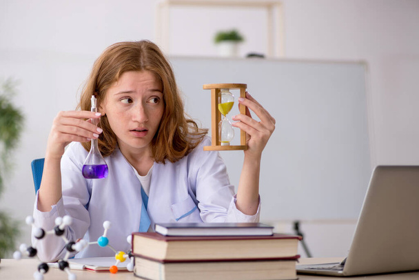 Young female chemist student in time management concept - Fotoğraf, Görsel