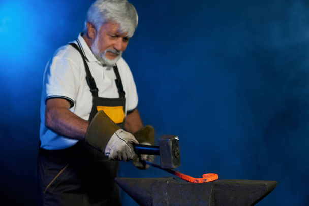 Skillful blacksmith forging molten steel on anvil  - Foto, afbeelding
