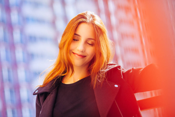 Smiling beautiful woman with red hair and closed eyes outdoors in red and blue colors - Zdjęcie, obraz