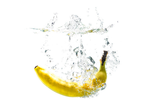 one banana falling into water on a white background with splashes - Foto, Imagen
