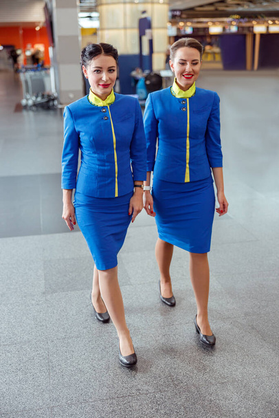 Χαρούμενες γυναίκες αεροσυνοδοί που περπατούν στο αεροδρόμιο - Φωτογραφία, εικόνα