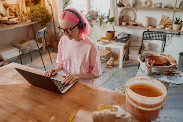 Woman potter using laptop in art studio - 写真・画像