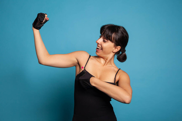 Portrait of athletic fit woman in sportwear showing am muscles - Fotoğraf, Görsel
