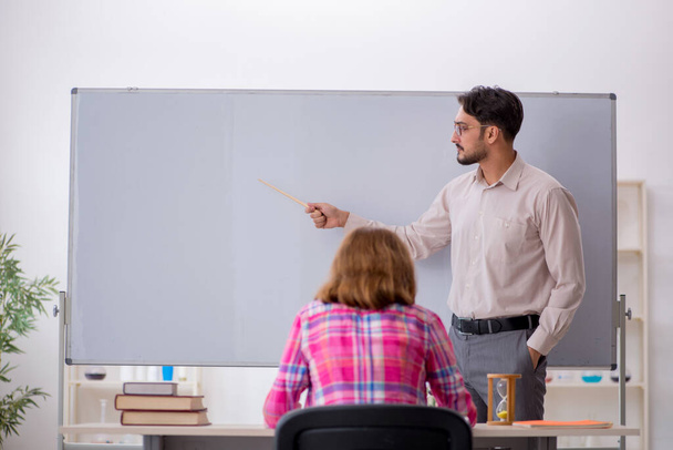 Jeune professeur masculin et rousse fille dans la salle de classe - Photo, image