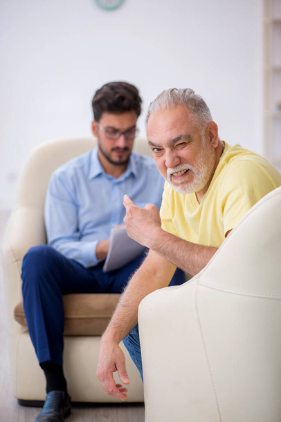 Yaşlı adam genç erkek psikoterapisti ziyaret ediyor. - Fotoğraf, Görsel