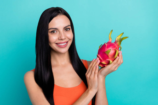Photo of positive cheerful lady vegan hold tasty yummy dragon fruit isolated over cyan color background - Foto, imagen