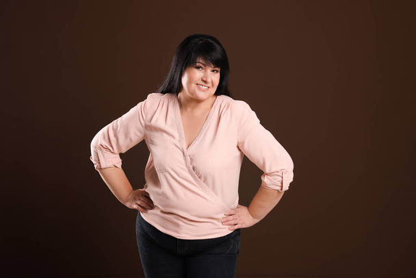 Beautiful overweight mature woman with charming smile on brown background - Foto, afbeelding