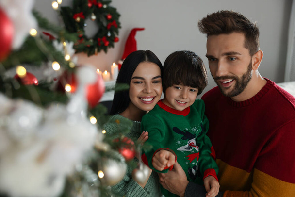 glückliche Familie schmückt gemeinsam Weihnachtsbaum zu Hause - Foto, Bild
