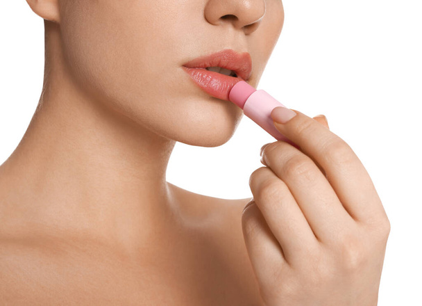 Young woman applying lip balm on white background, closeup - Фото, изображение