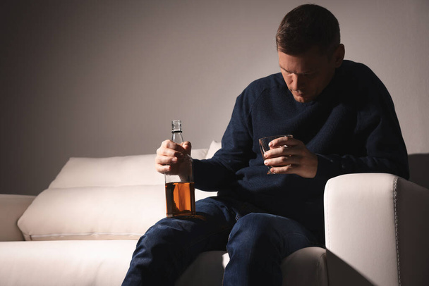 Addicted man with alcoholic drink on sofa indoors - Foto, imagen