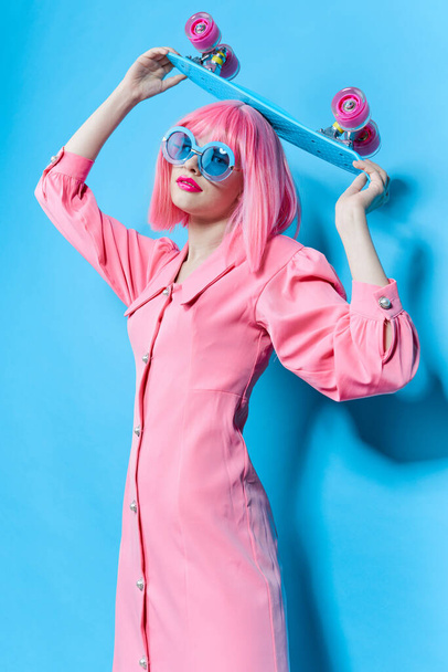 Güneş gözlüklü çekici kadın değiştirilmemiş pembe peruklu stüdyo modeli takıyor. - Fotoğraf, Görsel