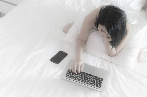 žena pomocí notebooku bílá na posteli bílá v ložnici domácí topview fotografie na soft focus sport - Fotografie, Obrázek