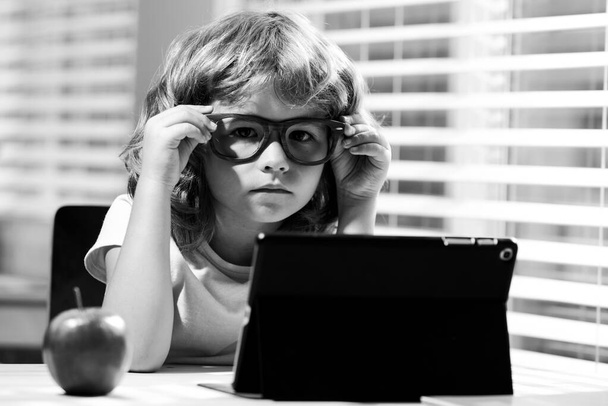 Child boy in glasses using a tablet and study online with video call teacher at home, homeschooling, distant learning E-learning, homeschool and online education for kids. - Foto, Imagem