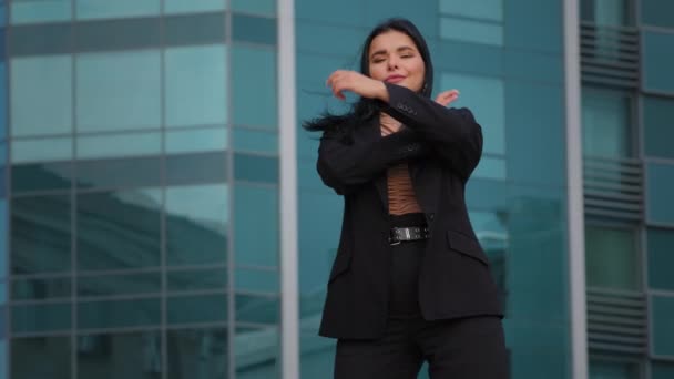 Jonge Spaanse zakenvrouw werknemer bedrijf staat zelfverzekerd armen gekruist buiten op achtergrond kantoor gebouw kijken naar camera poseren in succesvolle pose voelt zich tevreden met carrière groei - Video
