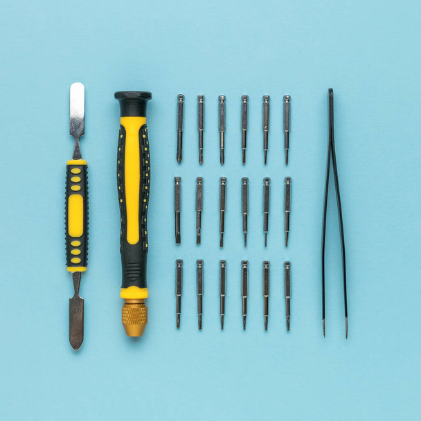 Werkzeuge aus Schraubendreher und Pinzette auf blauem Hintergrund. Zubehör zur Reparatur. - Foto, Bild