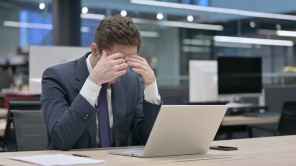 Empresario que tiene dolor de cabeza mientras trabaja en el ordenador portátil
 - Metraje, vídeo
