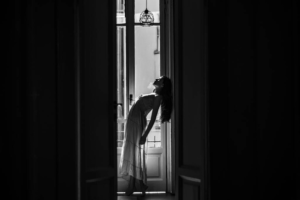 Woman meets morning near balcony. She happy dances. Girl is dressed in nightwear. Young woman standing near balcony. Relaxation and comfort moment day off. - Foto, Bild