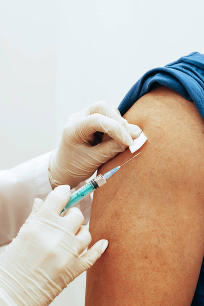 Lekarz szczepi człowieka. Zbliżenie selektywnej miękkiej ostrości. Światowa koncepcja szczepień COVID 19 - Zdjęcie, obraz