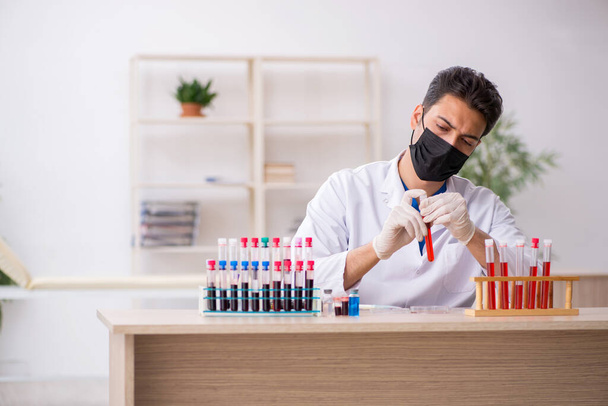 Junger männlicher Biochemiker testet Blutproben im Pandemiekonzept - Foto, Bild