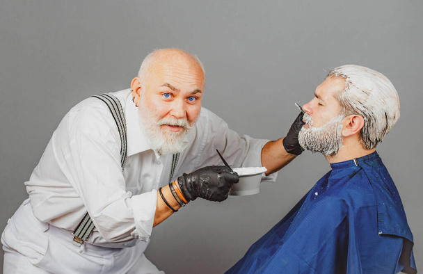 Hairdresser making of a color hair for hipster guy. Process of a man having his hair coloring at hairdresser salon. Barbershop procedures. - Foto, Imagem