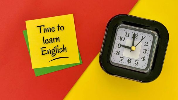 İngilizce öğrenme zamanı - sarı not defterinde mesaj. Alarmlı saat, kırmızı ve sarı arka plan. İş konsepti. - Fotoğraf, Görsel
