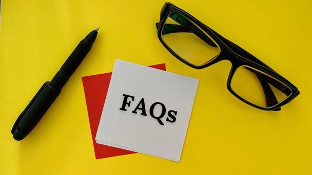 FAQs texto sobre poste blanco nota con pluma, gafas y fondo amarillo. Concepto empresarial. - Foto, Imagen