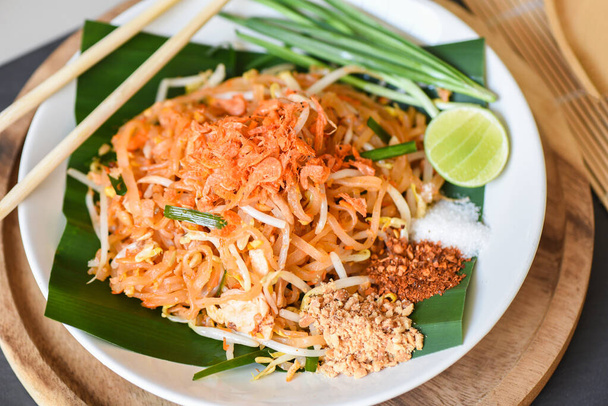 タイ料理フライドヌードルエビのもやしと飾るピーナッツチリパウダーシュガーレモンライム、炒め麺皿の上にタイ料理-トップビュー - 写真・画像