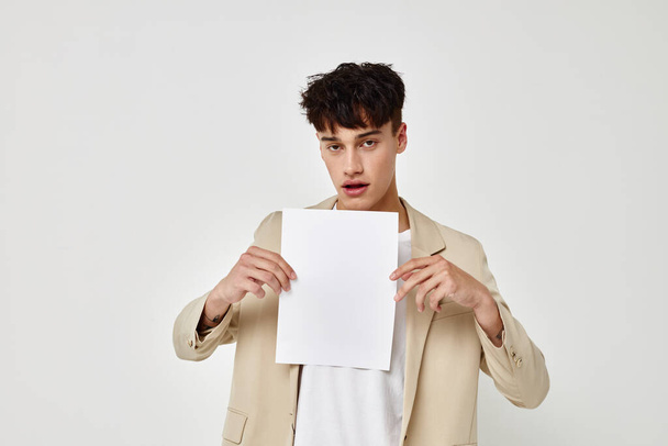 A young man in a beige suit copy-space folder with papers light background unaltered - Foto, Imagem