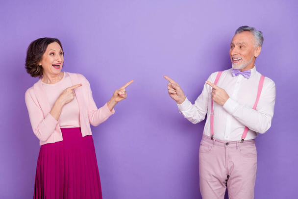 Portrait of aged stylish persons look direct fingers empty space each other isolated on violet color background - Фото, зображення