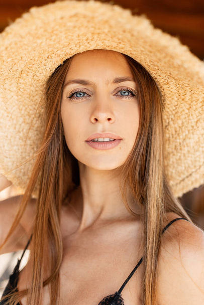 Schöne Sommer-Porträt der hübschen jungen Frau mit erstaunlichen blauen Augen in einem gewebten Strohhut spaziert am Strand und ruht im Urlaub - Foto, Bild