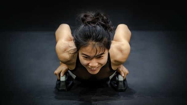 Young Asian athlete woman doing push up with push up bars on the floor. Strength Training in fitness gym - Photo, Image