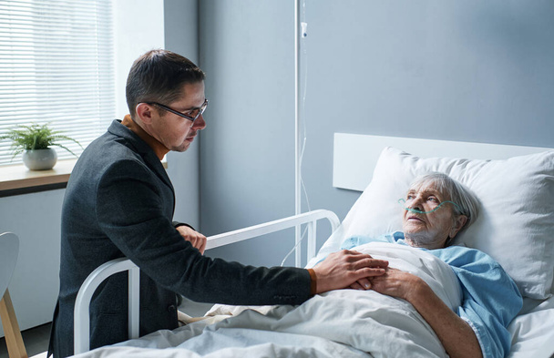 Sohn besucht kranke Mutter im Krankenhaus - Foto, Bild