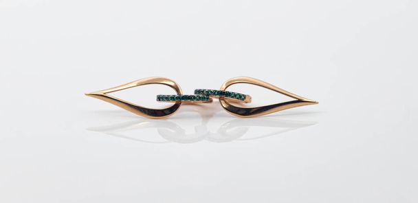 Gouden oorbellen in de vorm van een druppel met smaragd inzetstukken - Foto, afbeelding