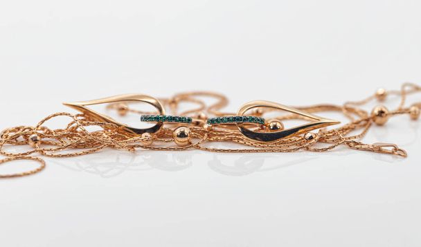 Elegantes pendientes de oro en forma de gota con esmeraldas rodeados de un fino collar de oro - Foto, imagen