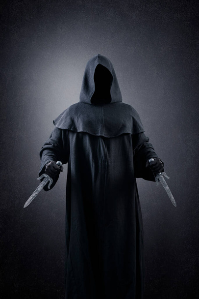Hooded assassin with two daggers in the dark - Foto, Imagen