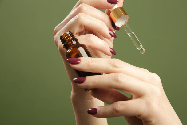 Handen vasthouden pipet en druppelaar glazen fles met olie. Natuurlijke cosmetica, essentiële olie, aromatherapie concept, huidverzorging concept. - Foto, afbeelding