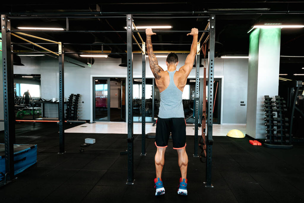 Portrait of professional athlete working out at gym, doing pull-ups and back training - Fotoğraf, Görsel
