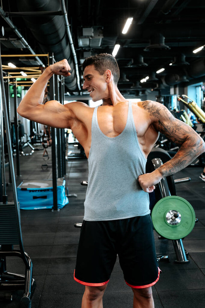 Professional healthy trainer and certified trainer working out. Portrait of muscular attractive man working out at gym, doing biceps muscle training and flexing muscles.  - Foto, imagen