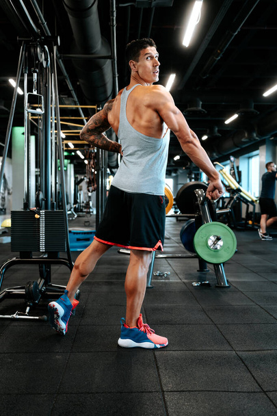 Professional healthy trainer and certified trainer working out. Portrait of muscular attractive man working out at gym, doing biceps muscle training and flexing muscles.  - Foto, Imagem