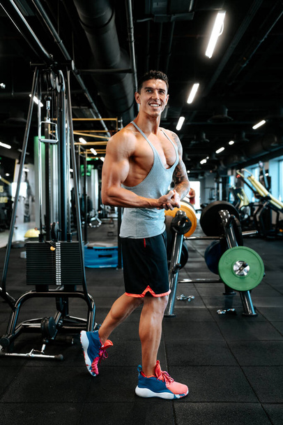 Professional healthy trainer and certified trainer working out. Portrait of muscular attractive man working out at gym, doing biceps muscle training and flexing muscles.  - Фото, зображення