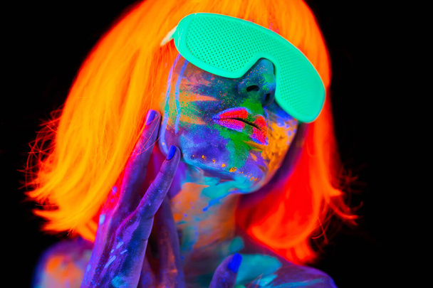 Beautiful model woman in wig and glasses with colorful bright fluorescent makeup in neon light, nightclub disco - Zdjęcie, obraz