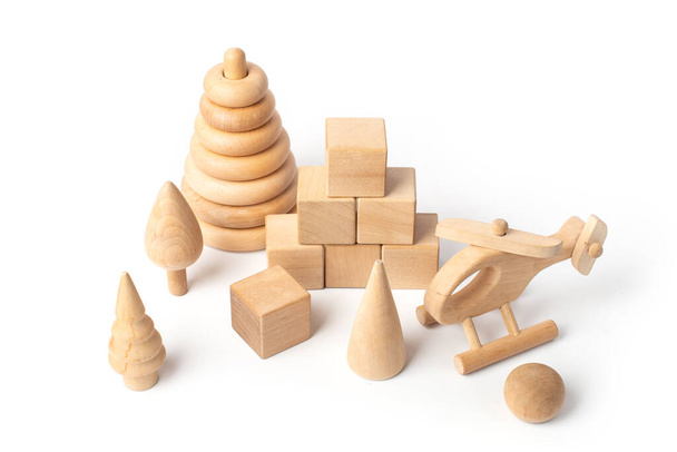 juguetes de madera sobre un fondo blanco, pirámide, cubos, bosque de madera, helicóptero - Foto, imagen