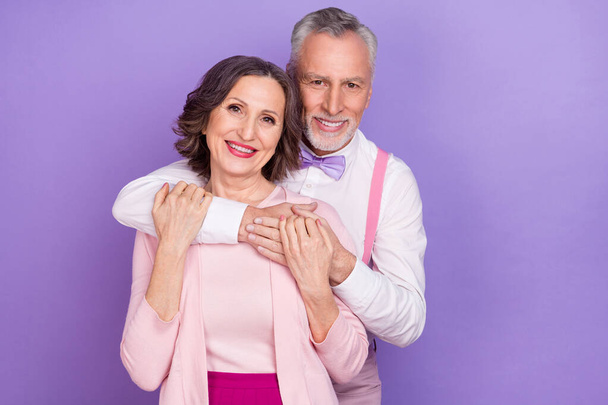 Portrait of two idyllic cheerful elderly partners hug trust care isolated on violet color background - Foto, imagen