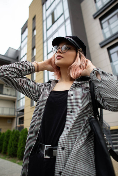 Urban moda młoda kobieta model w modnych ubrań casual i vintage czapka z okularami i torba spacery na ulicy w pobliżu budynku - Zdjęcie, obraz