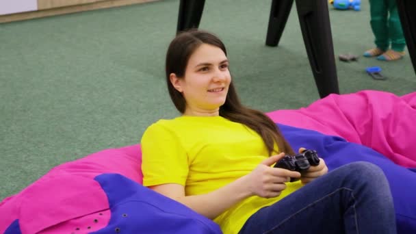Uma mulher joga um console de jogo, segura um joystick em suas mãos e sorri. - Filmagem, Vídeo