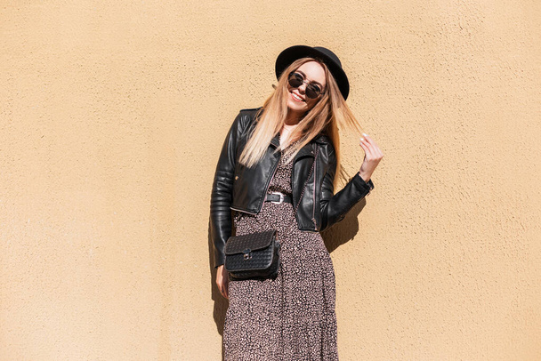 Happy fashion woman with autumn trendy outfit in stylish leather jacket and dress with black small bag - Photo, Image
