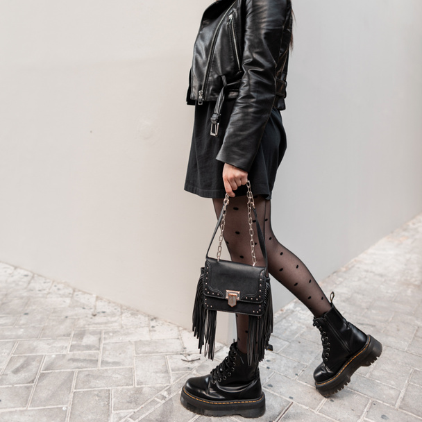 Mujer de moda de belleza en traje fresco negro con hermosas piernas sexy con medias y zapatos de moda con elegante bolso de cuero en la calle. Estilo urbano de las mujeres y moda - Foto, imagen