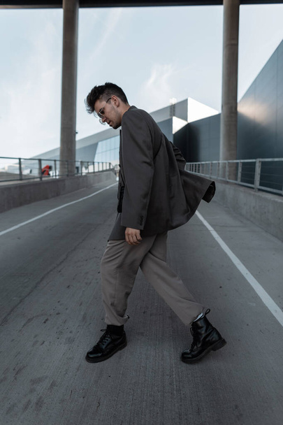 Stylový pohledný mladý muž model v módní elegantní oblečení vzhled procházky na městském pozadí. Muž ležérní styl a móda - Fotografie, Obrázek